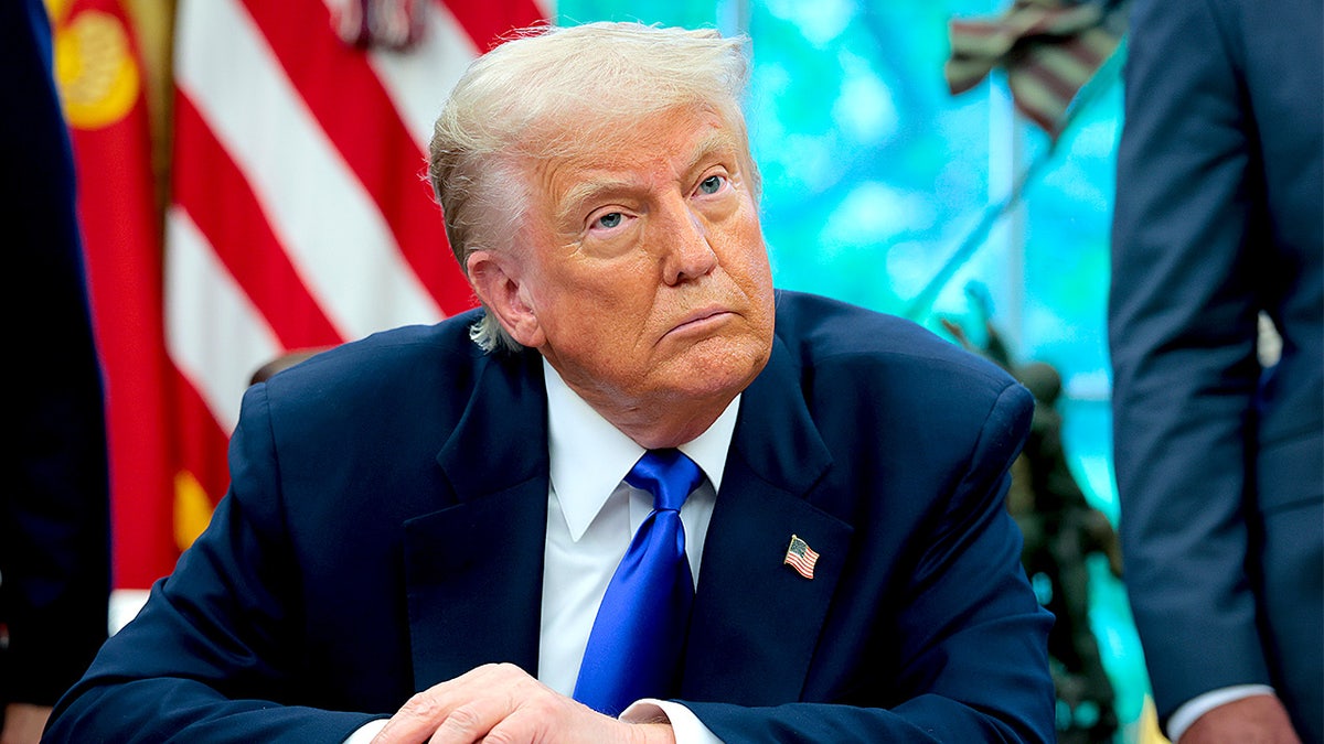 President Donald Trump takes a question from a reporter while seated in the Oval Office.