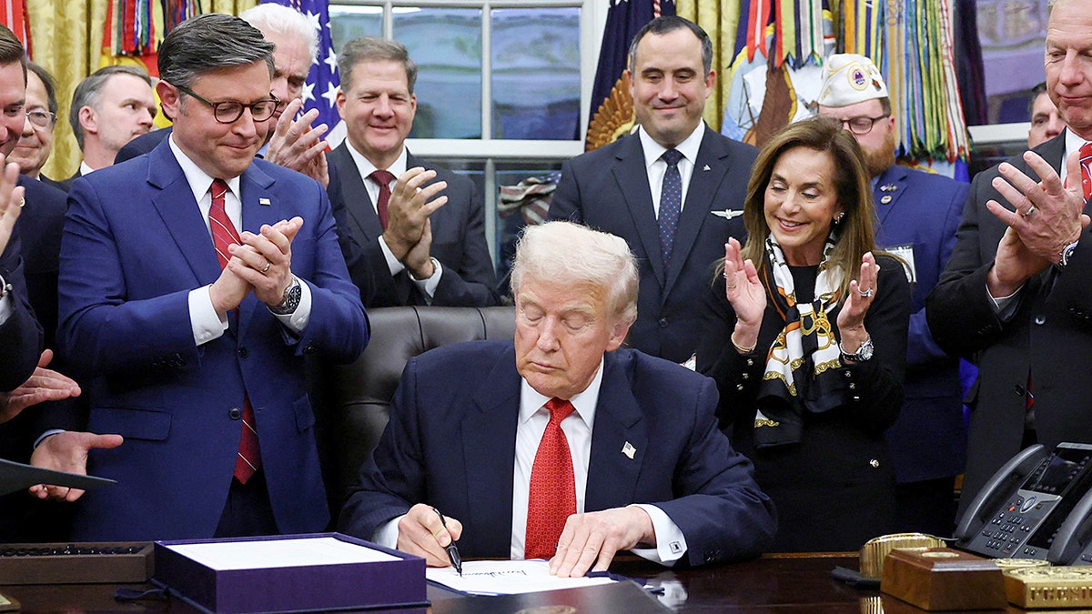 President Trump signs a measure  into instrumentality    surrounded by lawmakers