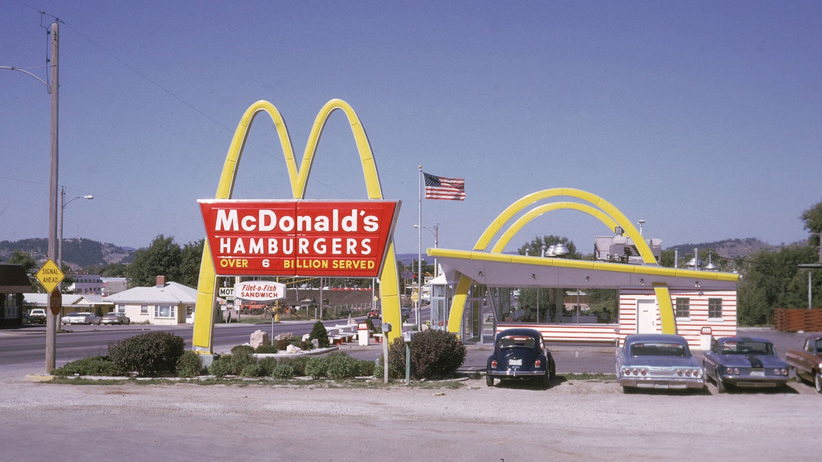 The exterior of a McDonald's fast food restaurant, USA, August 1970. The location of the outlet is possibly on Interstate 90 in Rapid City, South Dakota. Vintage cars seen out from next to giant Golden Arches.