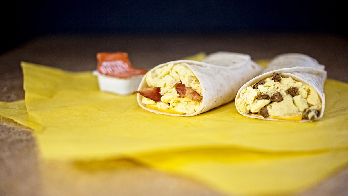 Two Whataburger Taquitos sit on a table next to an open sauce packet.