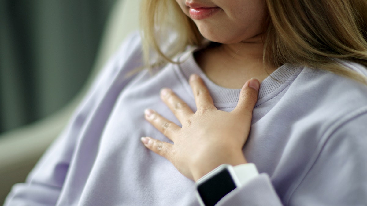 Younger person coughing touching chest