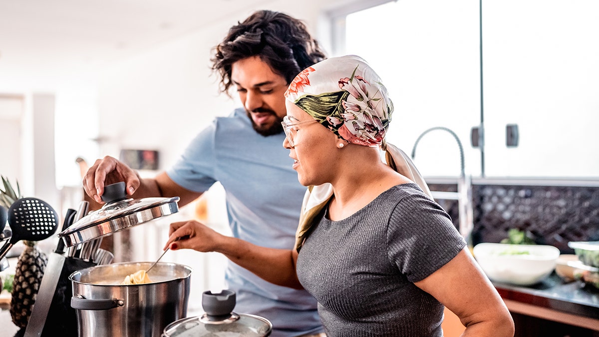 ক্যান্সারে আক্রান্ত মহিলা চুলায় একটি পাত্র নাড়াচ্ছেন যখন মানুষ ঢাকনা তুলেছে