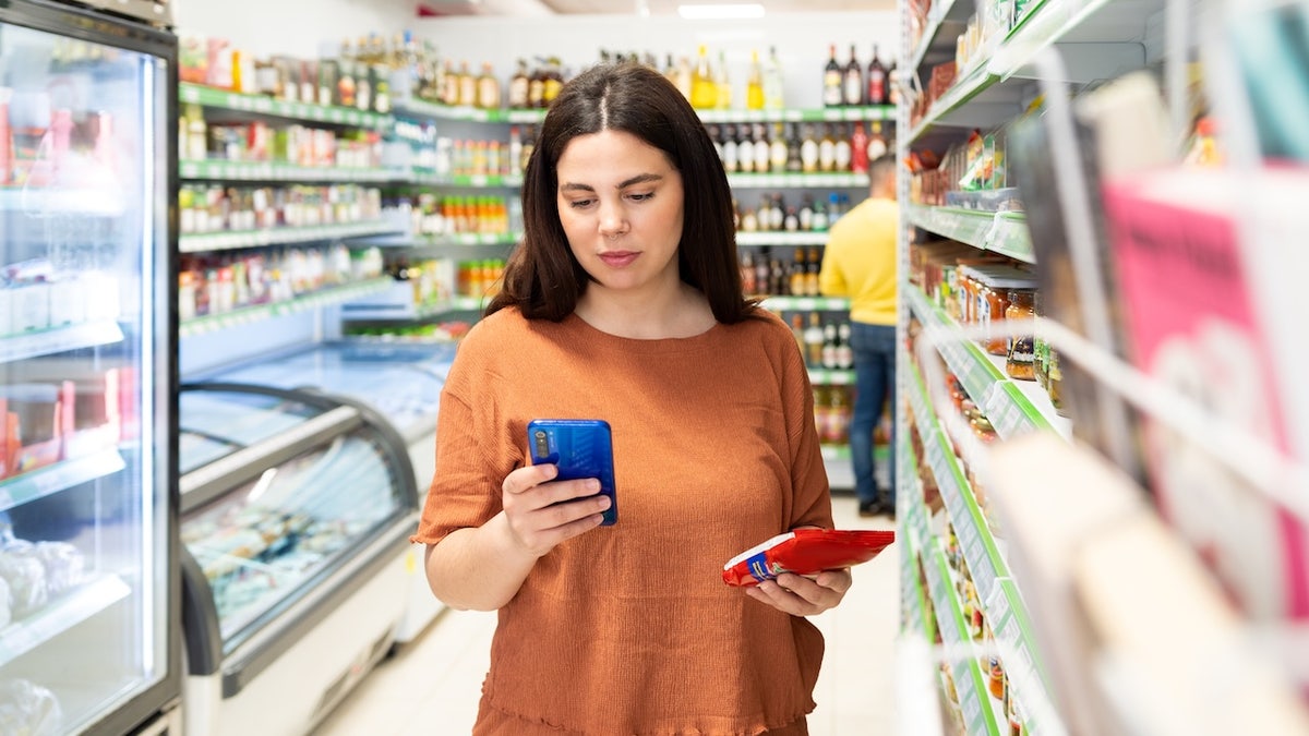Woman grocery shopping looking at food label