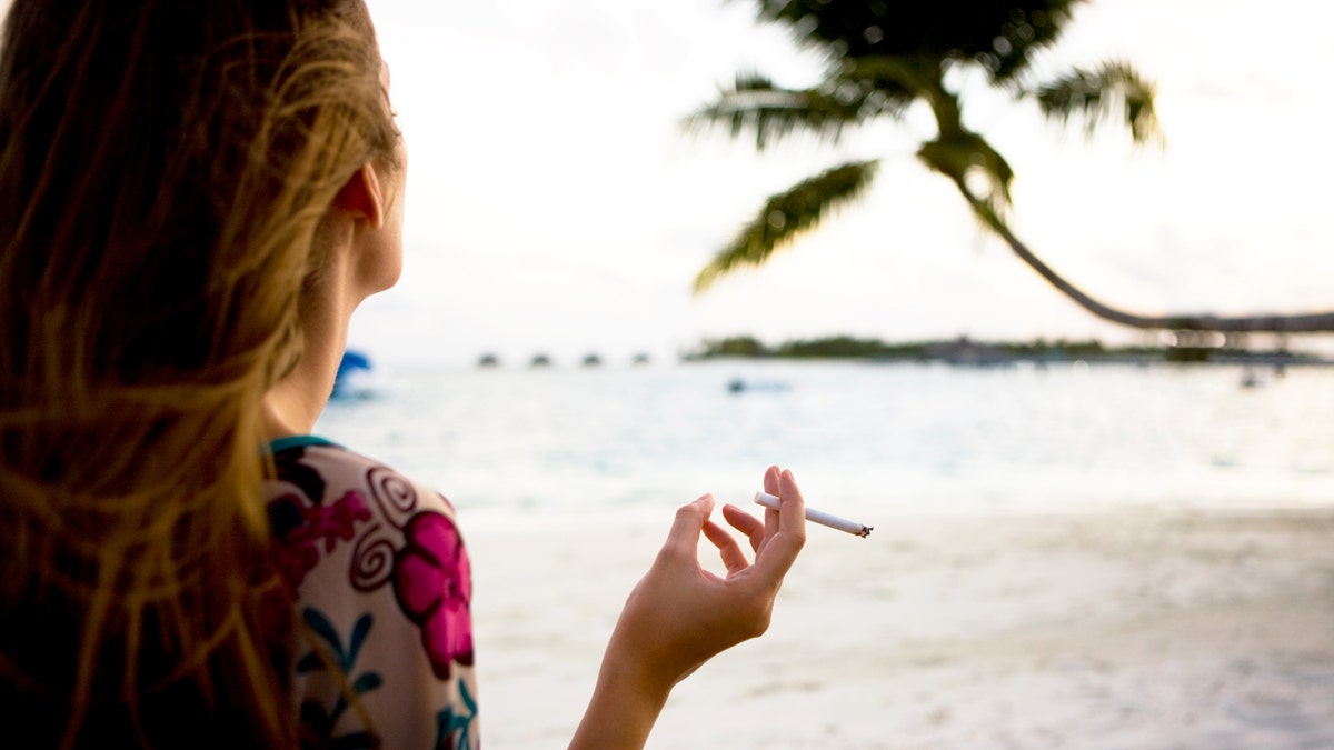 back of woman smoking on beach