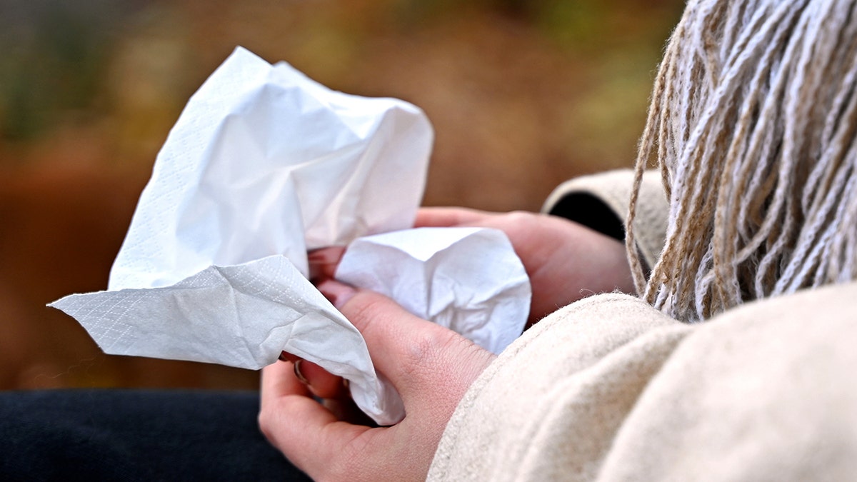 A woman sits on a park bench and holds a handkerchief