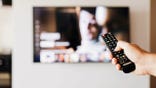 A remote control points at a television.