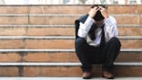 A man sits on stairs in a public place with head in hands.
