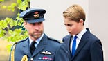 Prince William walking ahead of Prince George in uniform.
