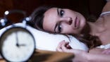 A woman is wide awake at 3 am in the morning.