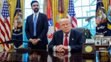 Zohran Mamdani stands next to President Donald Trump, who is sitting at desk in Oval Office