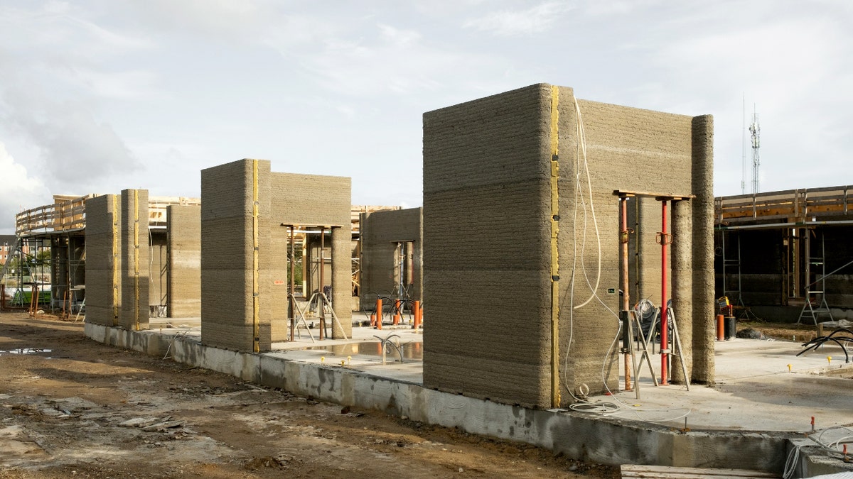Rows of 3D-printed concrete walls stand on foundations as student apartments take shape at a construction site.