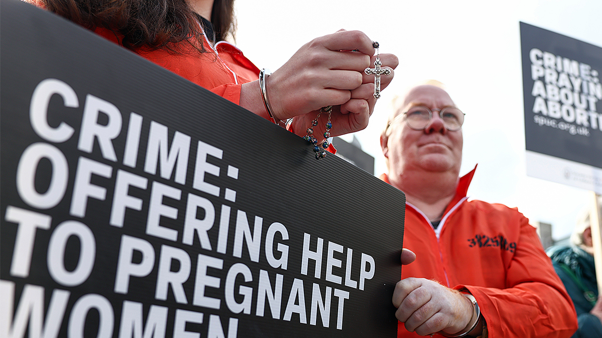 Anti-abortion protesters hold signs protesting abortion buffer zone law