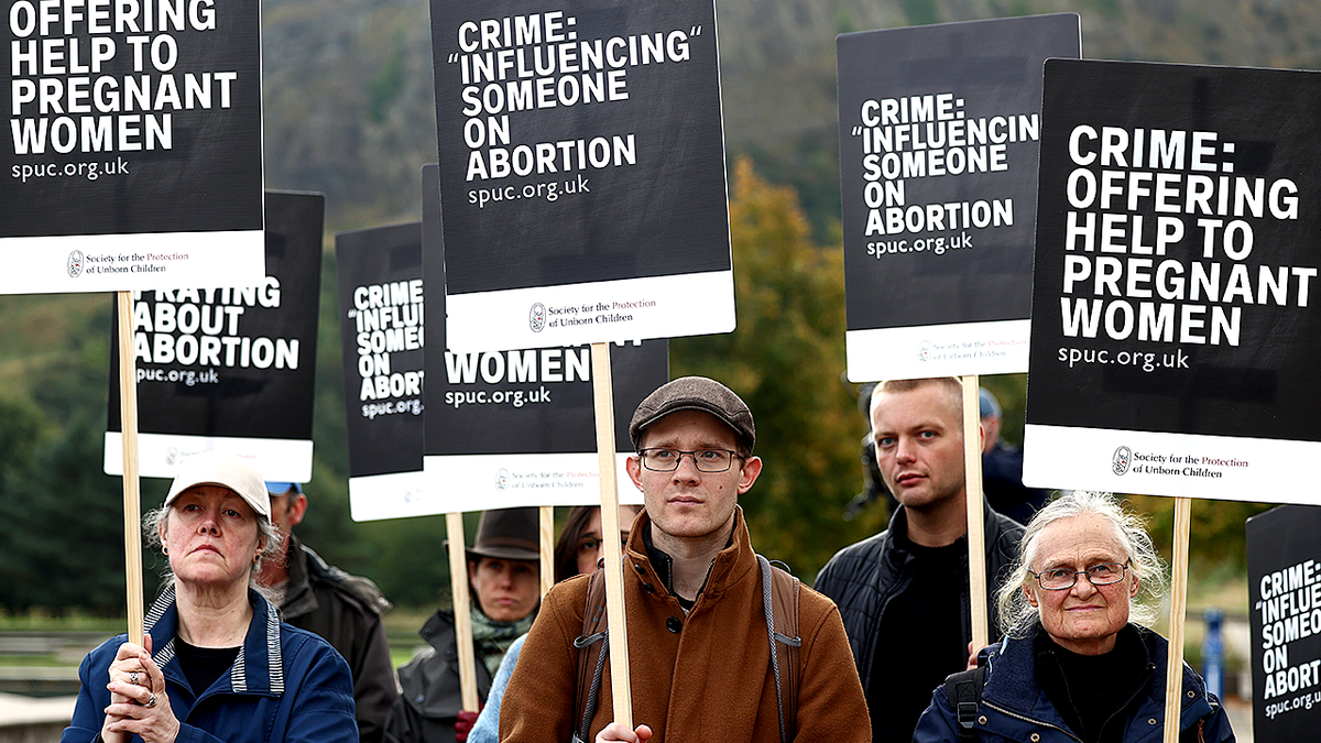 Anti-abortion protesters hold signs protesting abortion buffer zone law