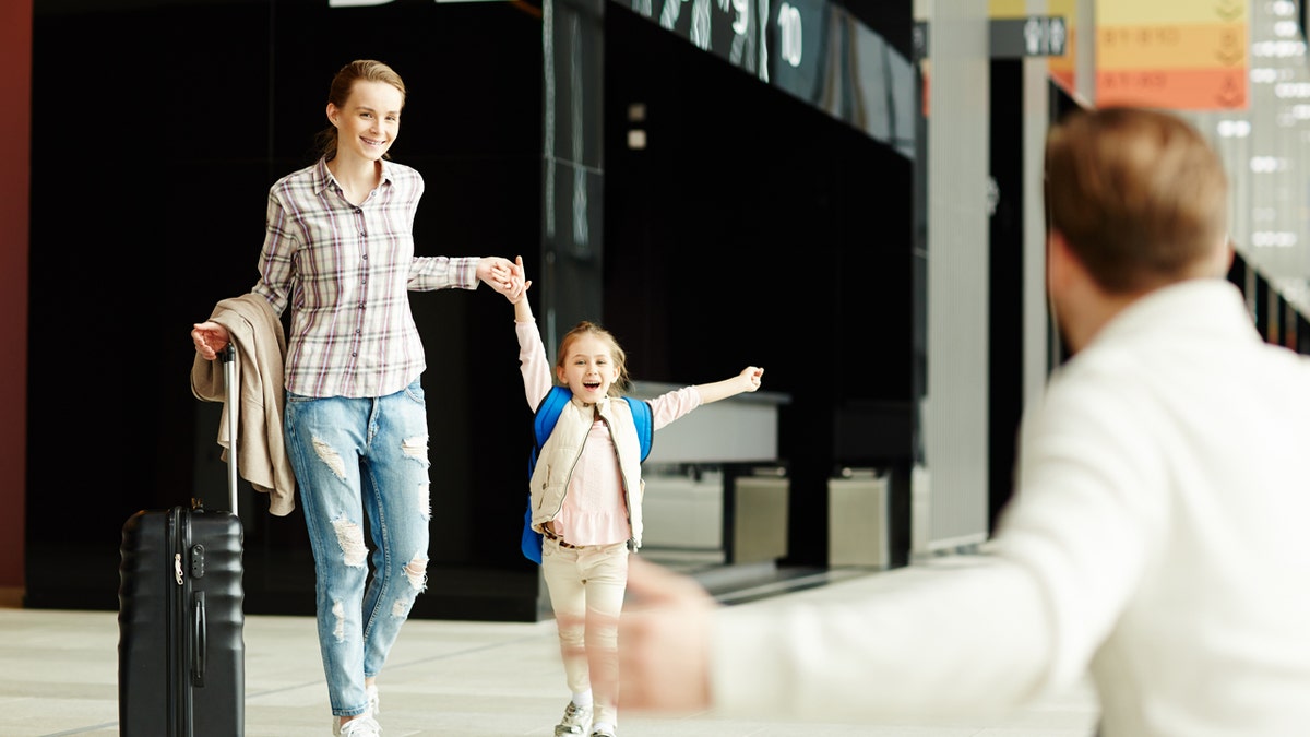 girl running at airport to meet father with mother