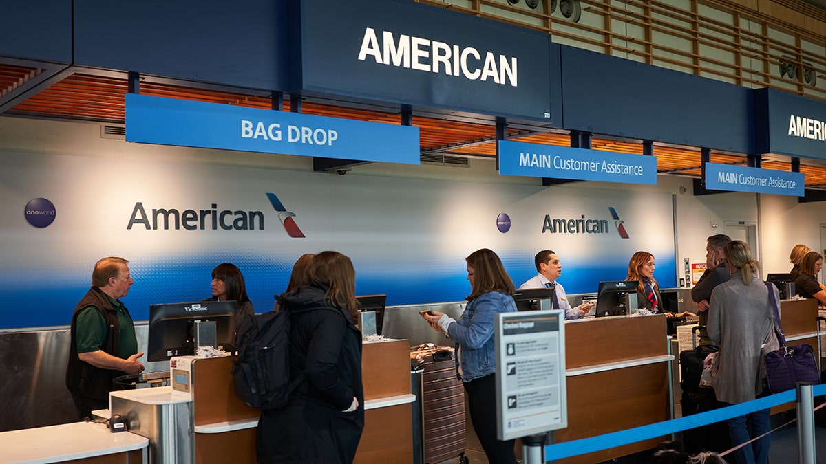 Passengers dropping off their luggage at the American Airlines bag drop off desk.