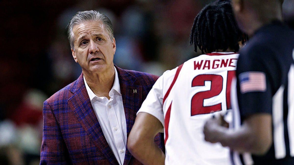 Head coach John Calipari talking with an official during a basketball game at Bud Walton Arena.