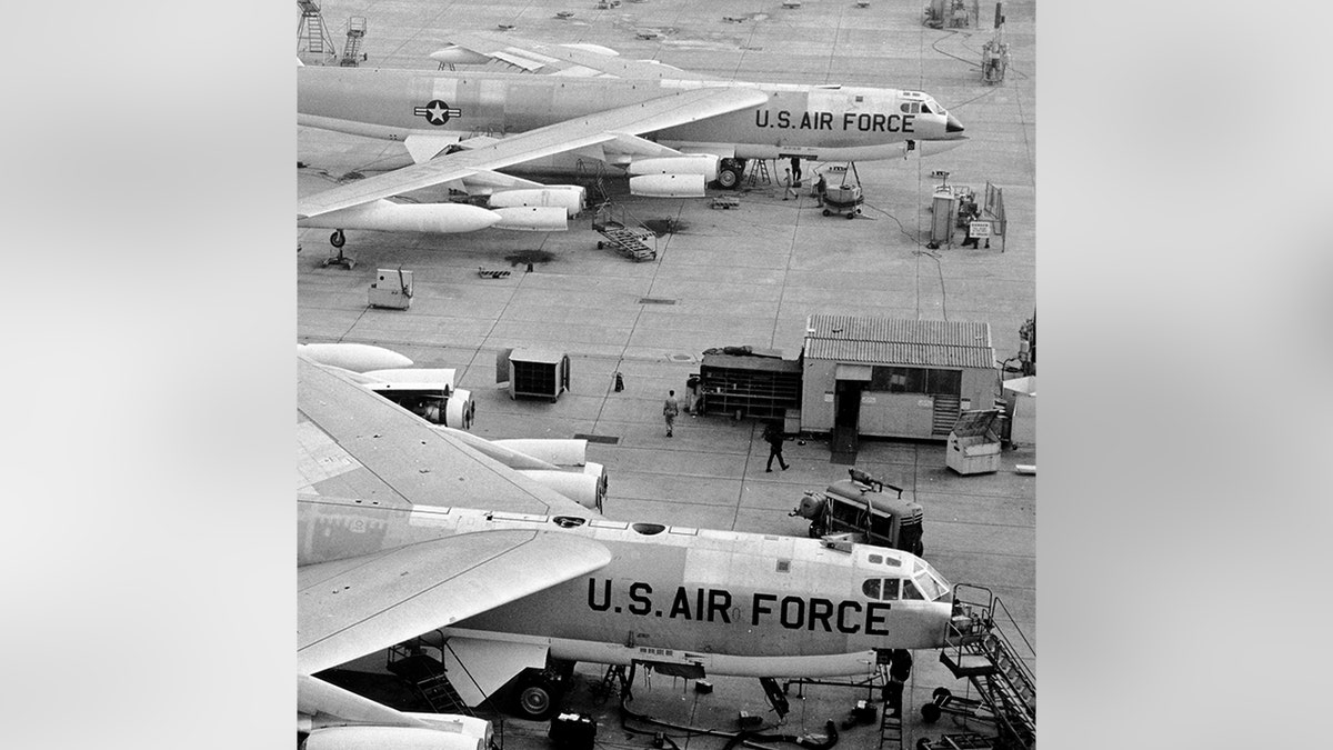 U.S. Air Force B-52 bombers sit on a military airfield as ground crews work nearby.