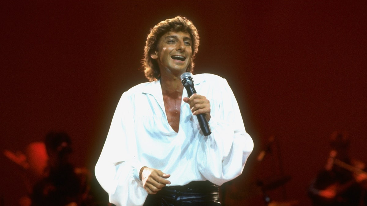 Barry Manilow wears a white top while performing on stage