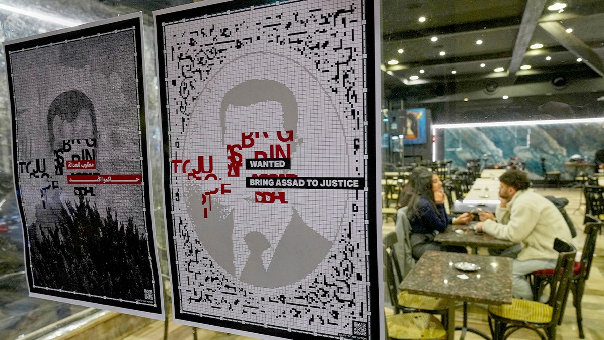 Posters of a deposed leader are displayed in a shop window during public celebrations.