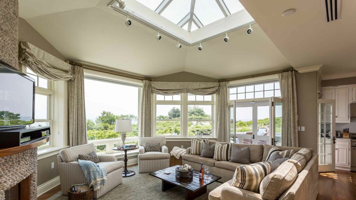 優雅的海洋屋客廳配有大窗戶、中性色調的家具和中央天窗，讓自然光充滿整個空間。