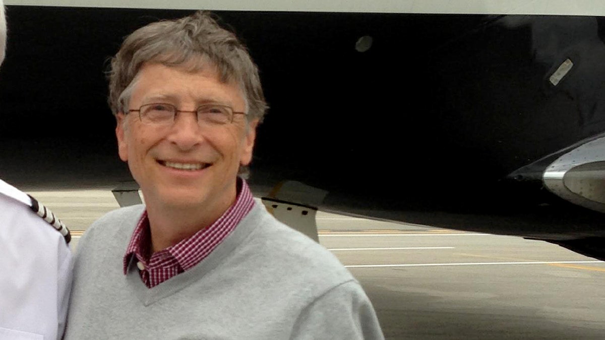 Bill Gates standing in front of a plane