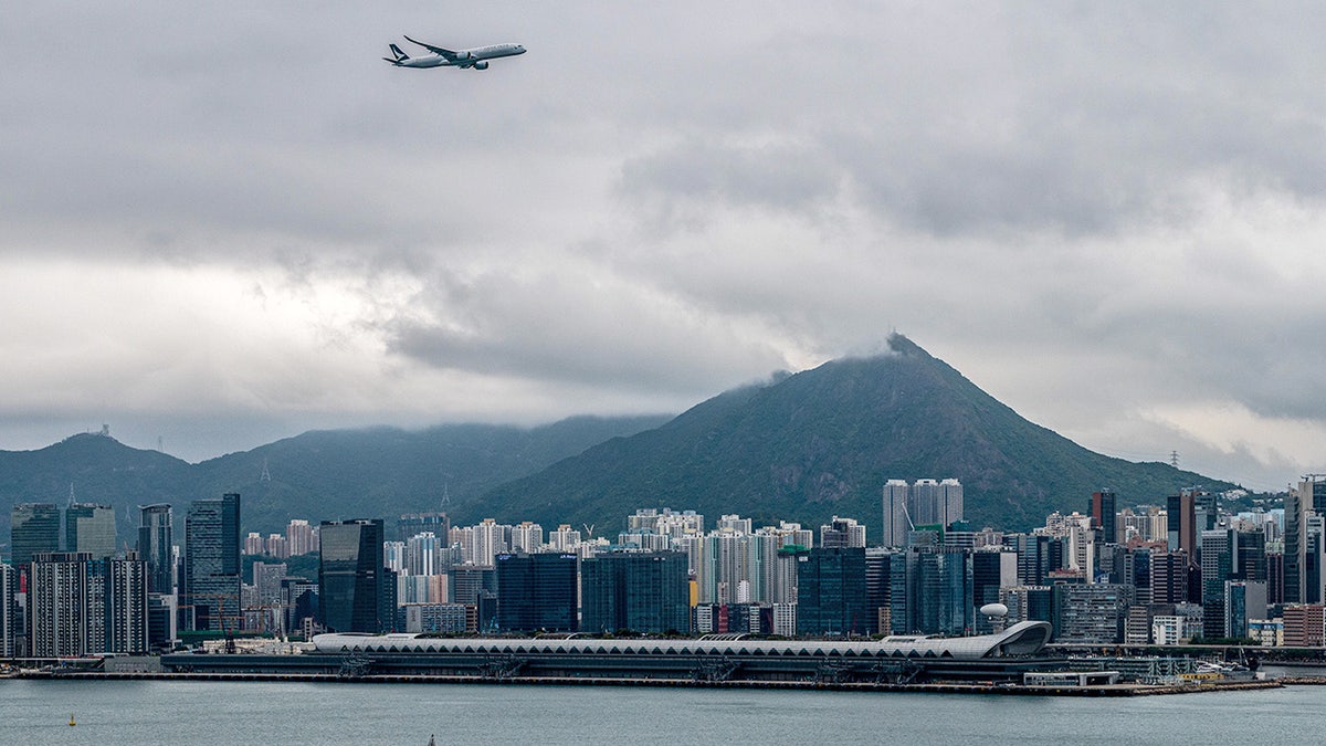 Cathay Pacific passenger plane flies over skyline of Hong Kong