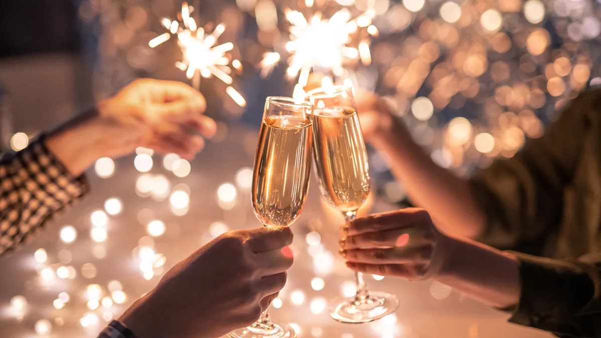 A group of friends "cheers"-ing to New Year's eve with glasses full of champagne