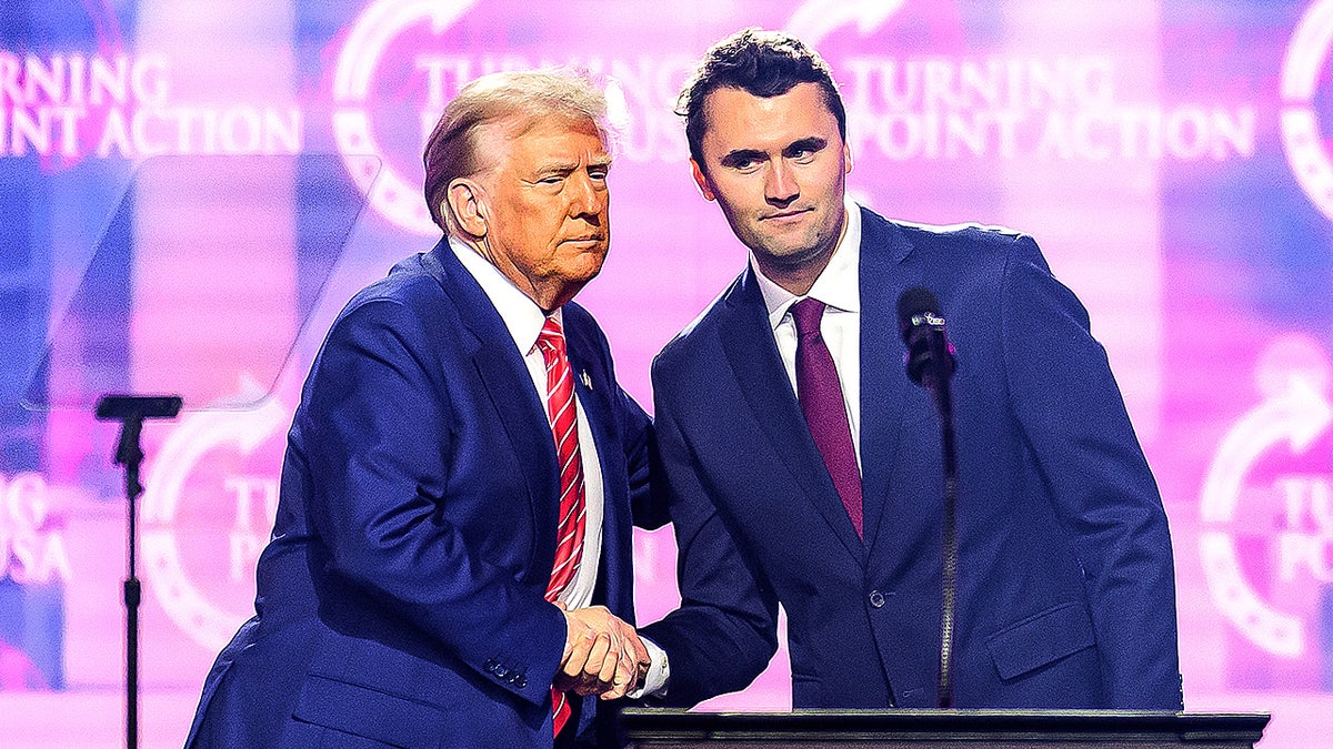 Charlie Kirk shakes hands with President Donald Trump onstage during a conference appearance.