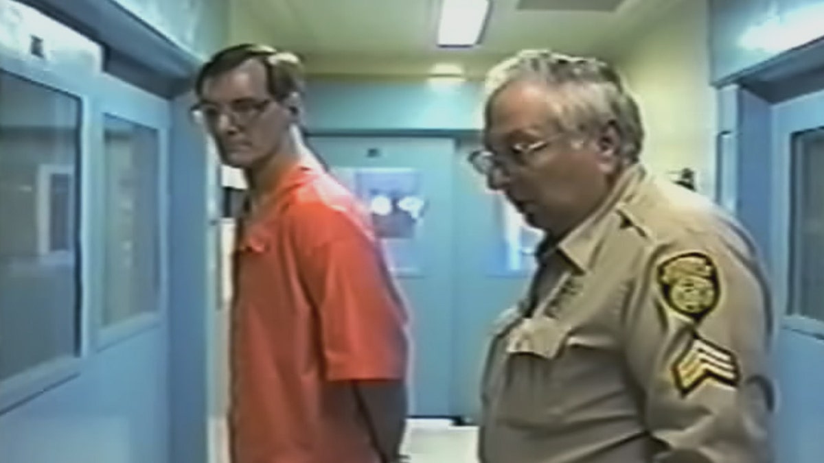 Doug Gretzler wearing an orange jumpsuit being taken to his cell.