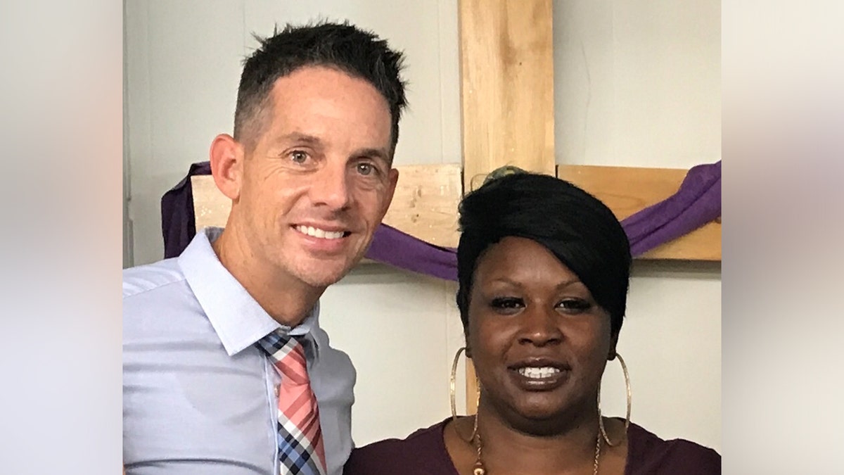A man and a woman standing to take a picture next to the cross in a church.