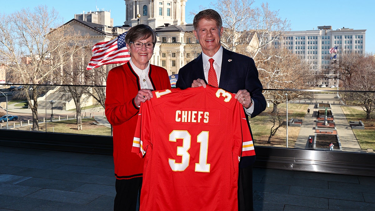 Chiefs owner Clark Hunt and Kansas Gov. Laura Kelly hold up uniform after announcing Chiefs move to Kansas.