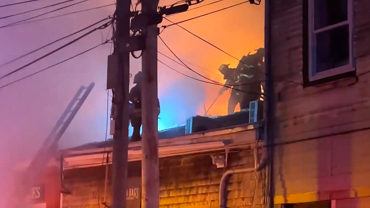 Firefighters attempt to stop fire on the roof of a building