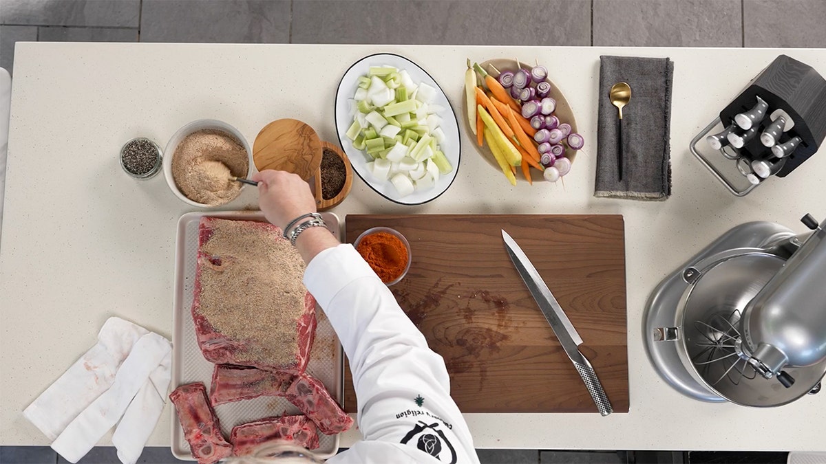 A chef puts cakes a prime rib with seasoning.