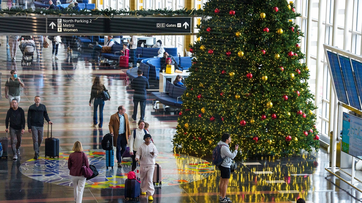 penumpang penerbangan berjalan di dekat pohon natal di bandara ronald reagan