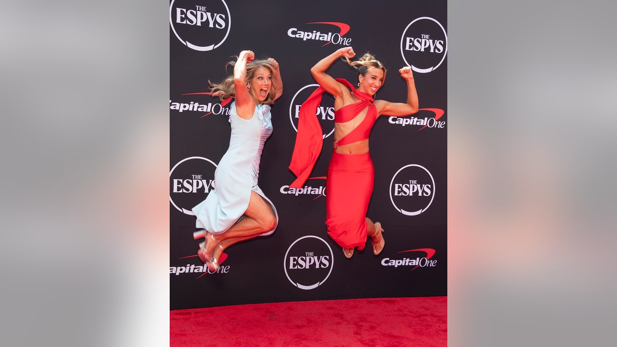 Denise Austin and her daughter Katie Austin jumping in the air wearing gowns.
