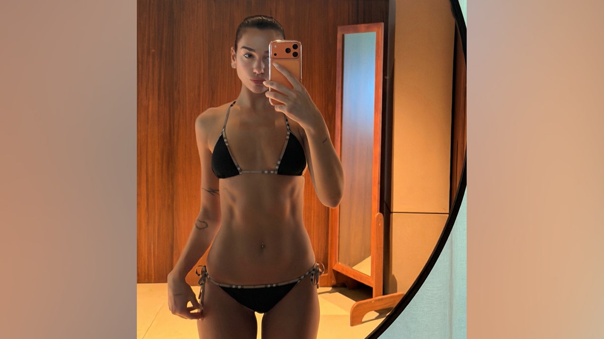 Dua Lipa poses for a mirror selfie in a black bikini.