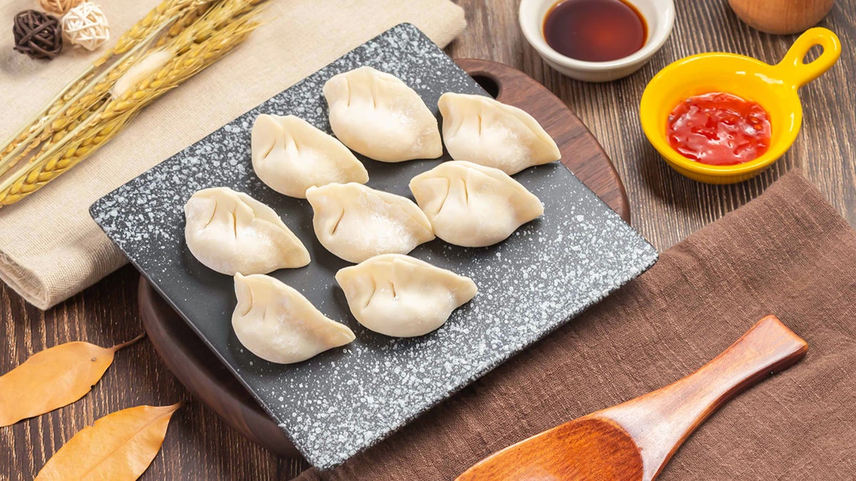 Dumplings on cutting board surrounded by spices and other ingredients.