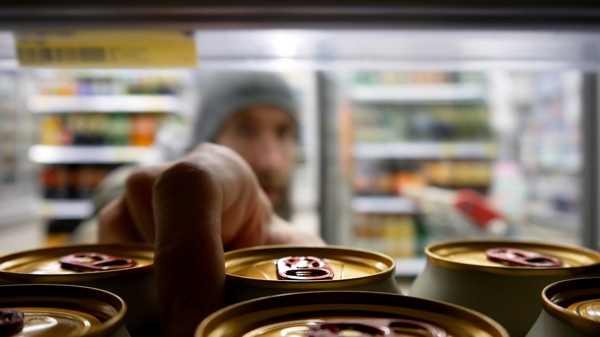 man reaches into fridge for energy drink in can