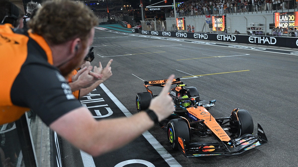 Lando Norris drives by his team