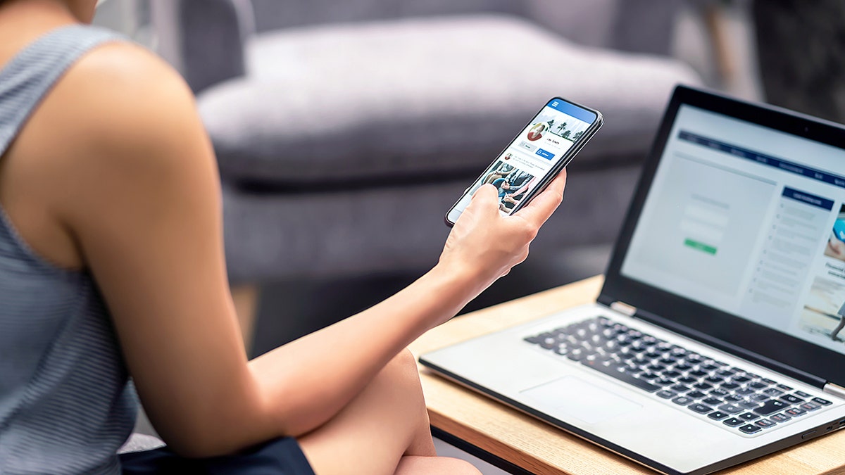 Woman looks at Facebook on phone