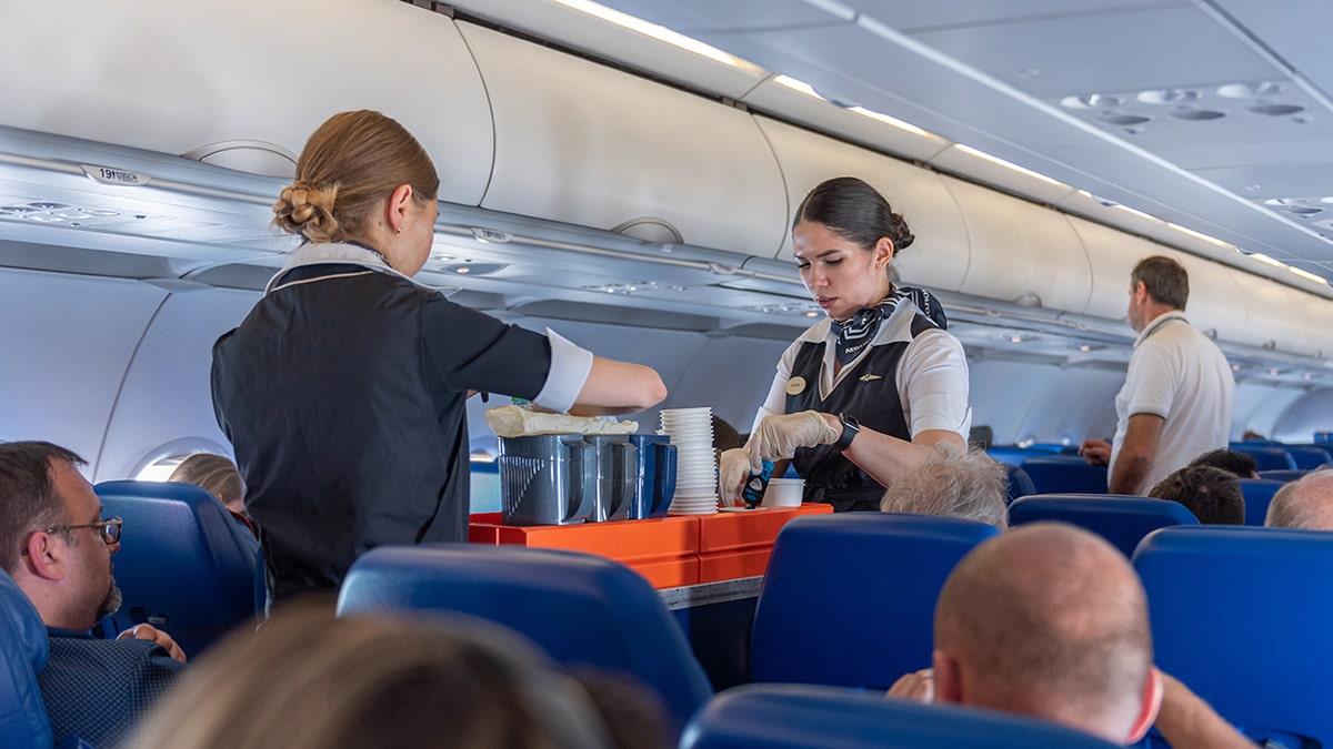 Female flight attendants are preparing coffee and beverages for passengers on the plane.