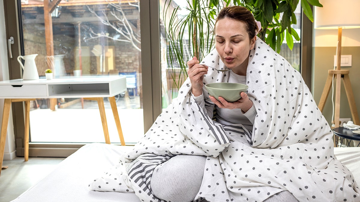 Woman eating soup while sick