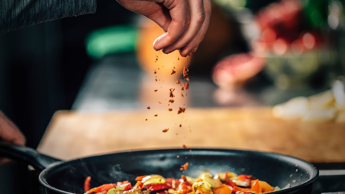 Man putting pepper in dish