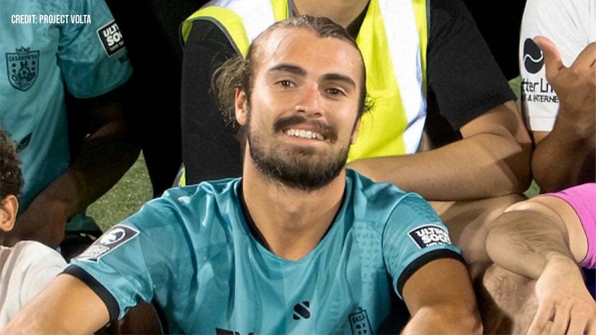 Soccer playing sitting on the grass for a group photo.