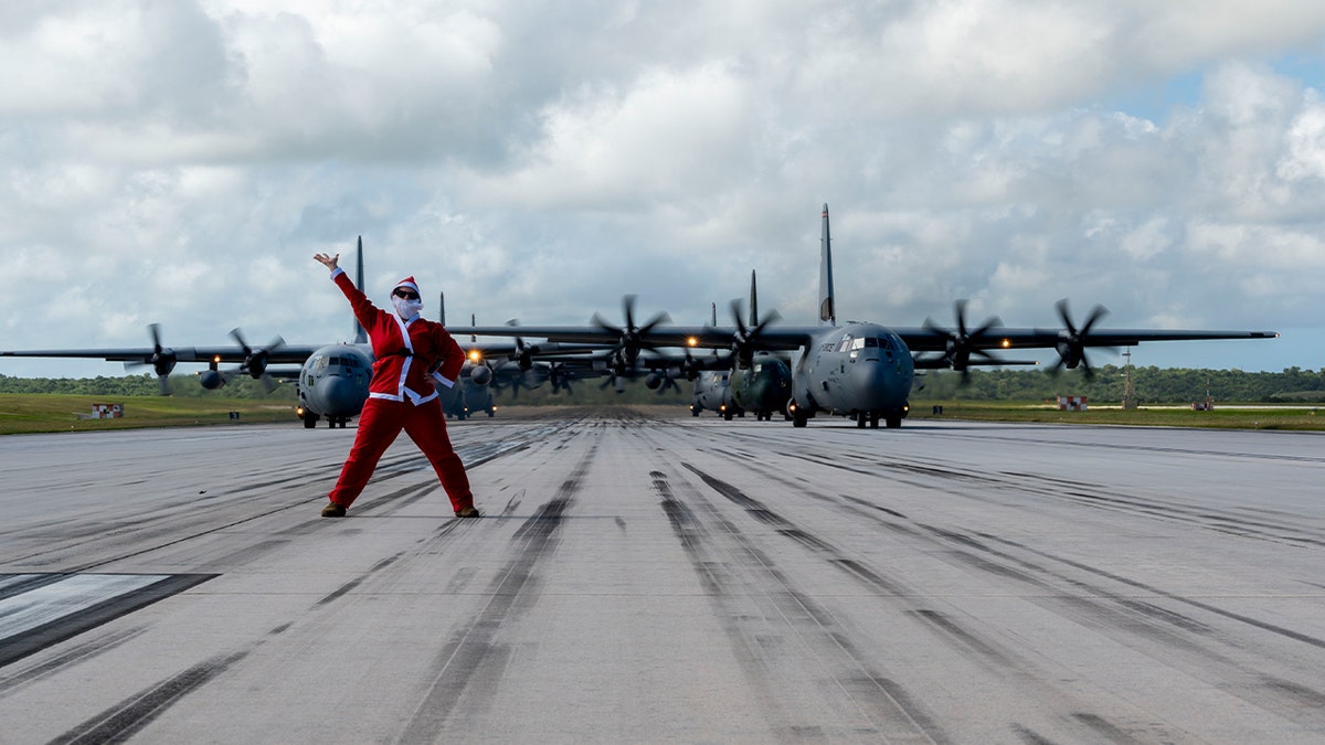 U.S. Air Force Lt. Col. Sara Wofford, 36th Airlift Squadron director of operations, stands before a formation of C-130J Super Hercules and C-130H Hercules aircraft from the U.S, Japan and Republic of Korea air forces participating in an elephant walk during Operation Christmas Drop 2025 at Andersen Air Force Base, Guam, Dec. 13, 2025