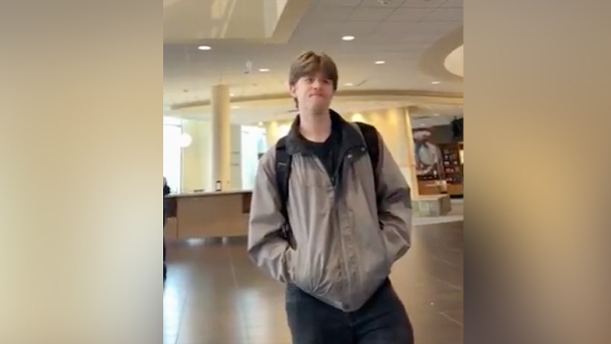 Student in beige winter jacket standing in campus building