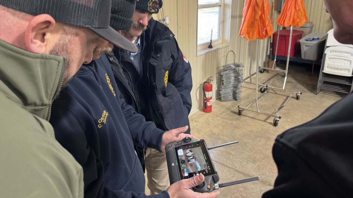 Hopkinsville Fire and EMS members reviewing aerial footage on a handheld device.