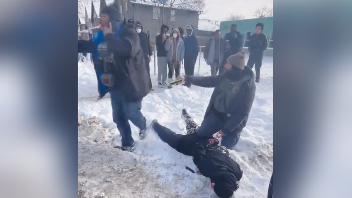 An ICE agent kneels on a woman