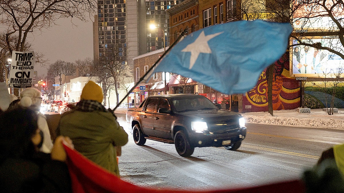 protestor waves somali flag on side of road