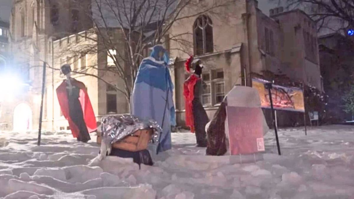 Wide nighttime Nativity scene with mannequins and ICE-themed figures in snow.